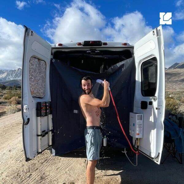 Man having a shower from Camplux AY132 at the back of a van